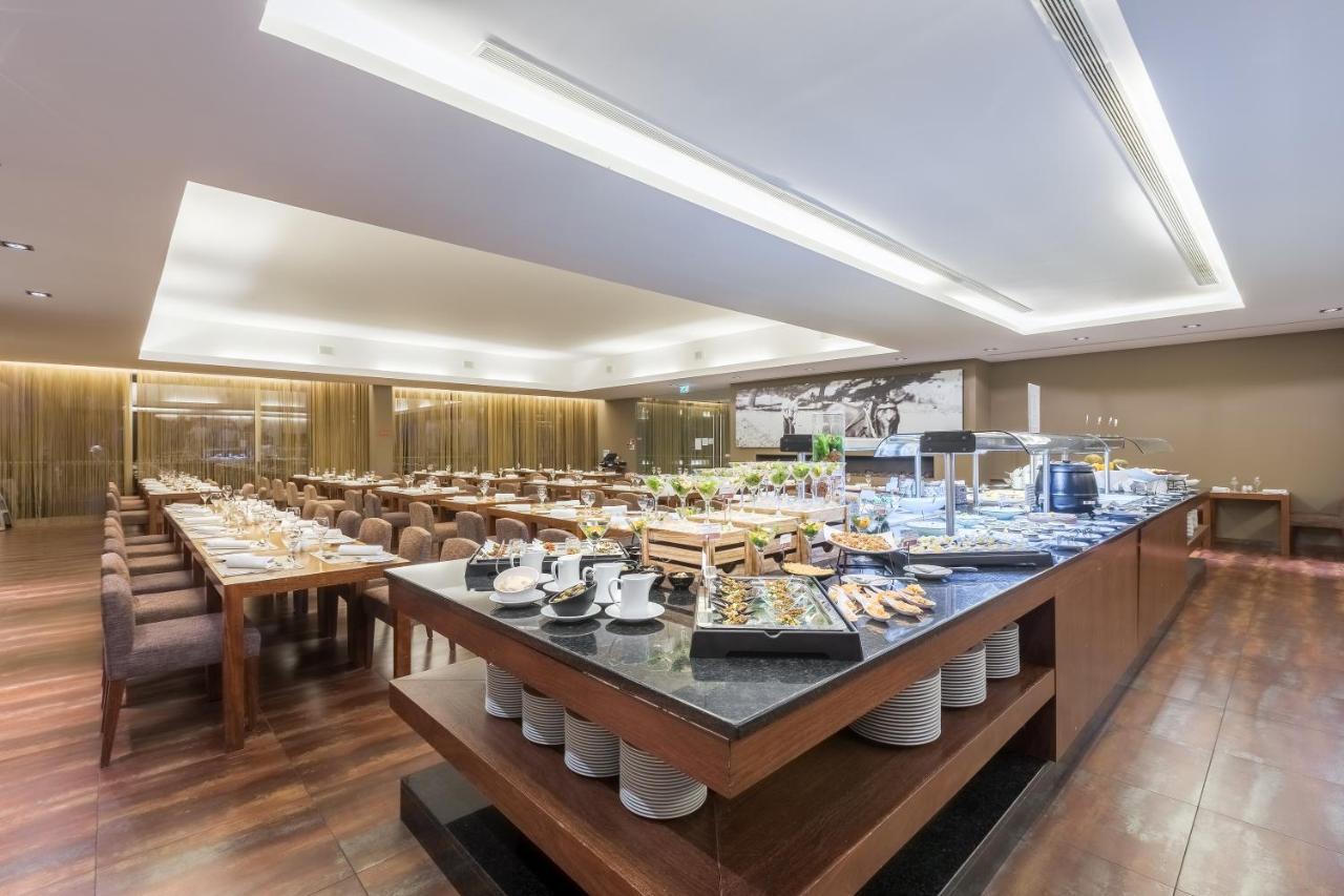 Ap Lago Montargil - Conference & Spa מראה חיצוני תמונה The photo displays a spacious restaurant interior, featuring a well-organized dining area with multiple tables set for patrons. In the center, there is a large buffet station filled with an array of food items. The decor is modern and elegant, with w