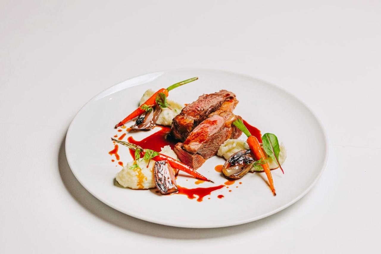 Ap Lago Montargil - Conference & Spa מראה חיצוני תמונה The photo features a beautifully plated dish. At the center, there are slices of a tender meat, likely beef, showcasing a juicy pink interior. Accompanying the meat are several elements: vibrant orange carrots, perhaps roasted or glazed, and dollops 