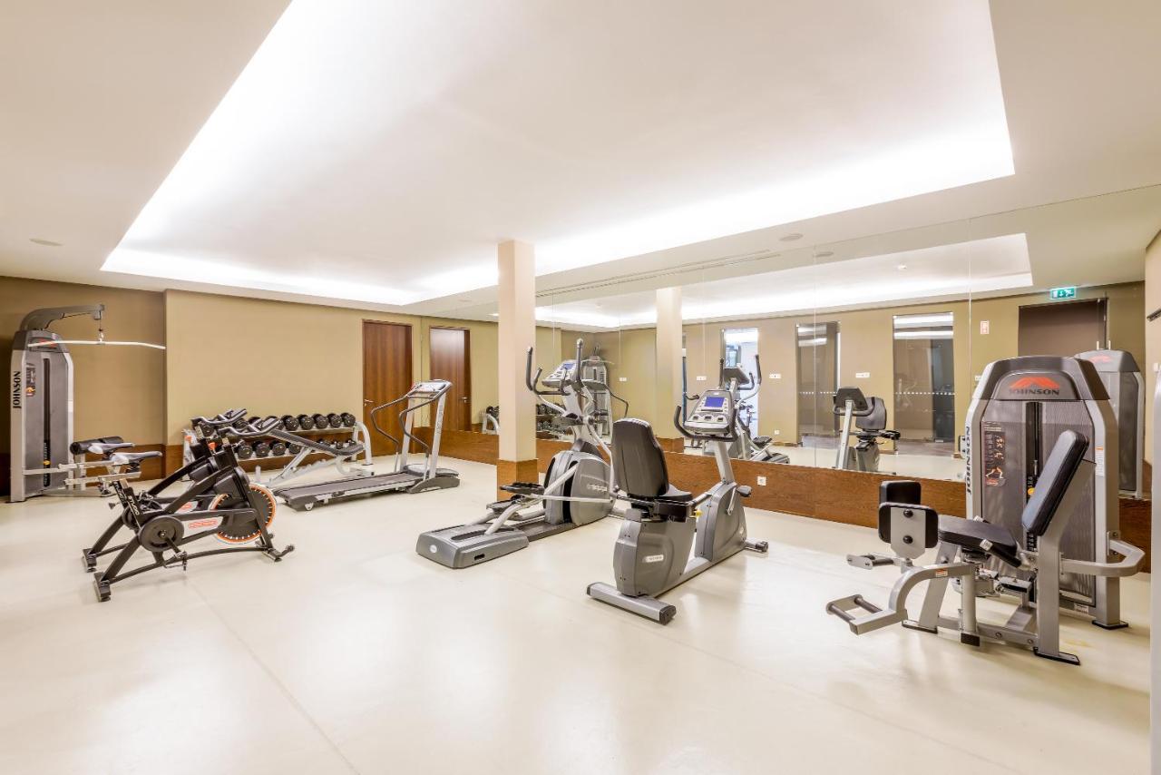 Ap Lago Montargil - Conference & Spa מראה חיצוני תמונה The image shows a modern gym interior featuring various exercise equipment. On the left, there are free weights and weight benches. In the center, there are multiple machines, including a stationary bike and an elliptical. The space is well-lit with 
