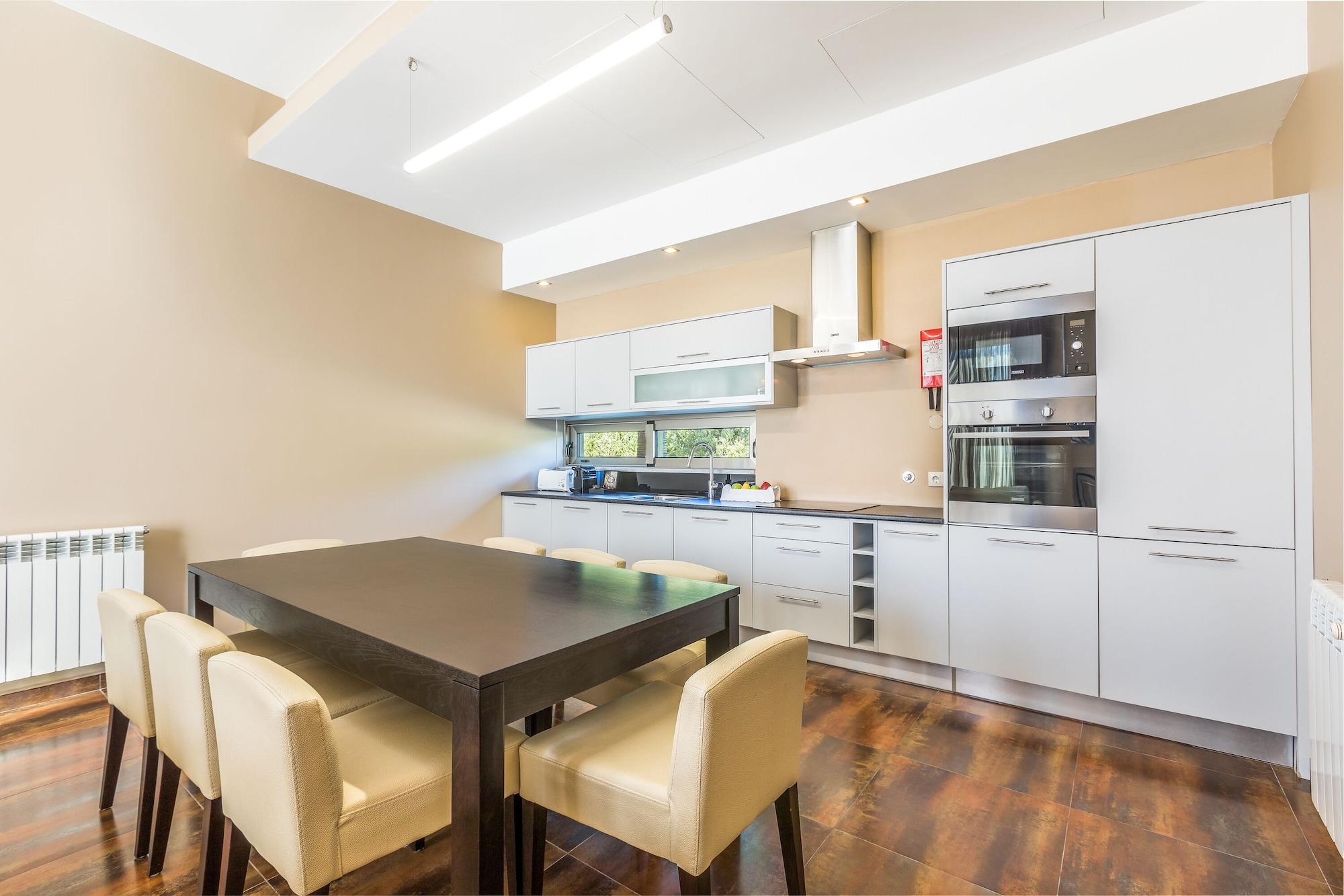 Ap Lago Montargil - Conference & Spa מראה חיצוני תמונה The photo shows a modern kitchen with a dining area. The kitchen features sleek, light-colored cabinets and countertops, including built-in appliances. There's a medium-sized dining table with dark wood and four light-colored chairs around it. The wa