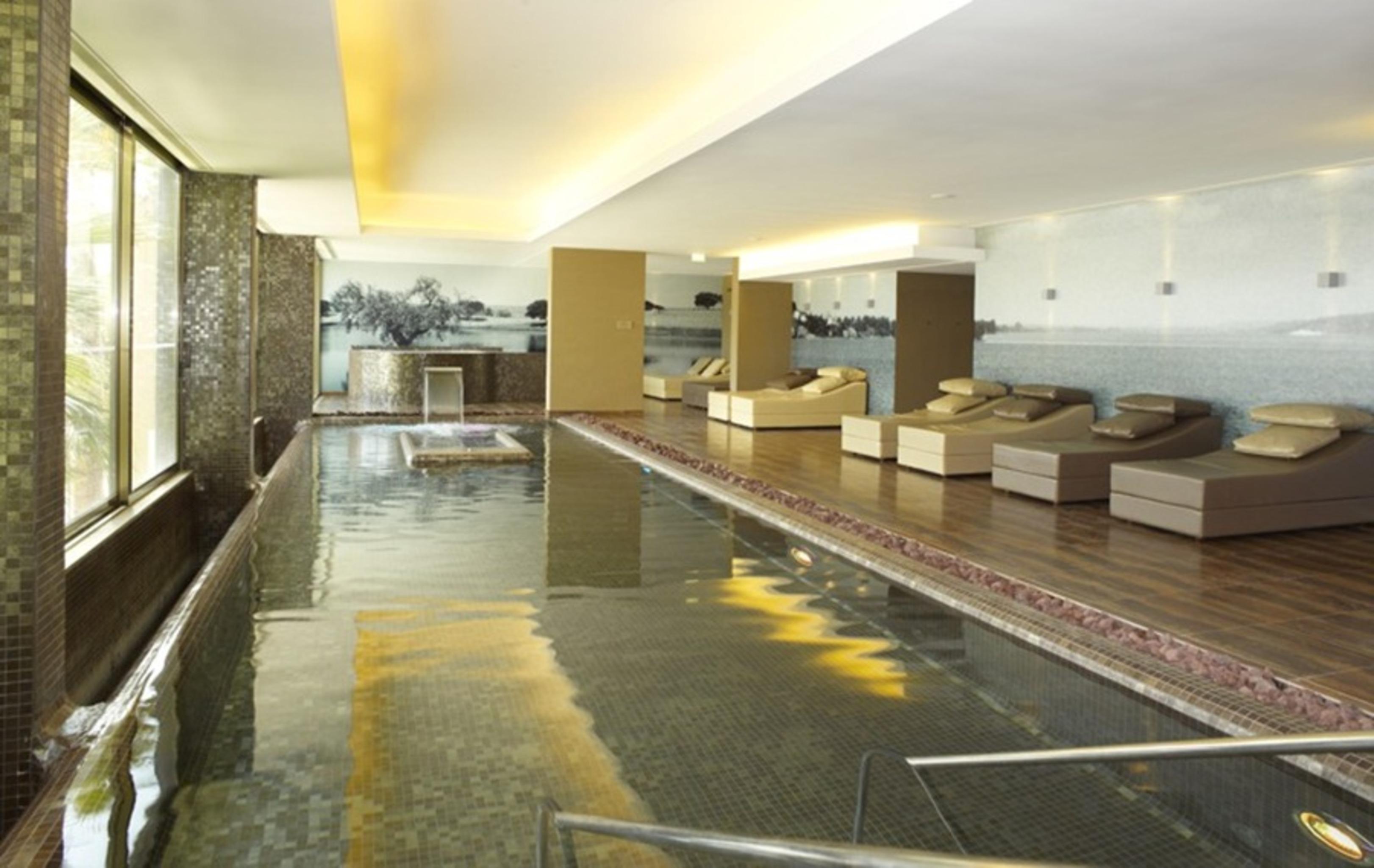 Ap Lago Montargil - Conference & Spa מראה חיצוני תמונה The photo shows a modern, serene spa environment. There is a swimming pool with calm water, reflecting the surrounding decor. Along the sides, there are several comfortable lounge chairs arranged, perfect for relaxation. Large windows allow natural l